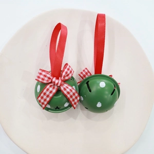 Close-up of green polka dot Christmas bells with red ribbon bows on a neutral dish