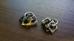 Detailed close-up of geometric square nested earrings in gold, silver and gun black finish