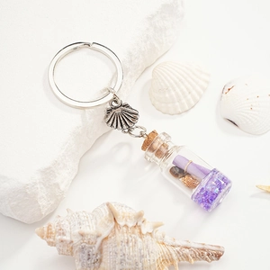 Close-up of glass bottle keychain with purple glitter, sea shells and paper scroll