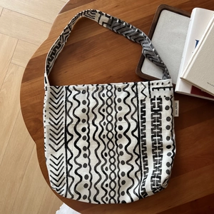 Detail of bohemian geometric print on white linen shoulder bag with a brand label