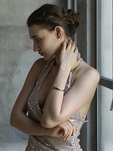 Detailed view of irregular twisted gold plated stainless steel bracelet on a woman wrist