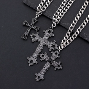Close-up of gothic cross pendants with intricate floral carvings and black gemstones