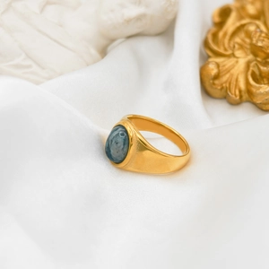 Macro detail of vintage 18k gold plated ring with oval blue agate on white silk