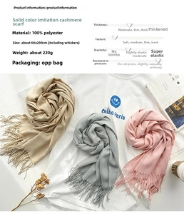 Detailed view of three solid color cashmere-feel scarves in beige, grey, and pink with tassels