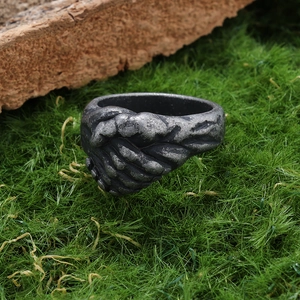 Détail macro d'une bague design poignée de main rétro sur fond de mousse verte