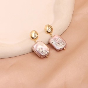 Detailed close-up of baroque pearls with gold plated zircon studs on a beige fabric