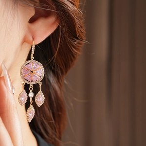 Close-up of vintage gold tassel earrings with pink zircons and rhinestones on model