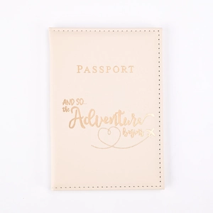 Beige PU leather passport cover with golden engraved adventure quote on white background