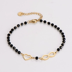 Detail of black beaded bracelet with gold heart and infinity charms on white background