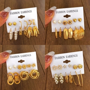 Dettaglio del set di orecchini dorati con forme geometriche, perle e cuori eleganti