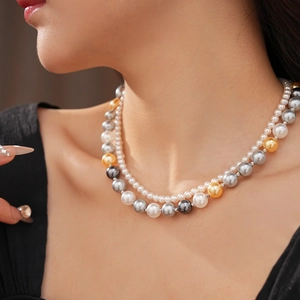 Gros plan d'un collier de perles à deux rangs avec perles blanches, grises et dorées