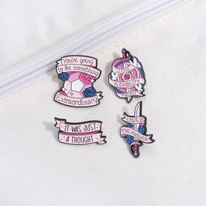 Détail de quatre épingles en émail rose avec citations motivantes sur fond de toile blanche