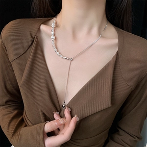 Baroque pearl lariat necklace with silver tassel on female model against black background