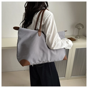Detailed side view of a large waterproof oxford tote with leather handles on a model