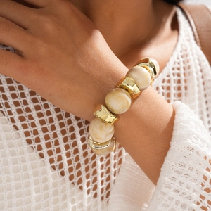 Detail of bohemian cream marble resin beads and polished gold metal bracelet on wrist