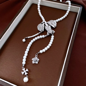 Detail of vintage pearl necklace featuring an antique silver bird pendant with tassels
