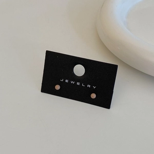 Macro shot of minimalist pastel pink bead stud earrings on a premium black jewelry card