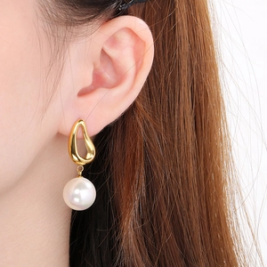 Close-up of elegant gold irregular hoop earring with a large white pearl on a model