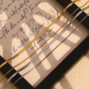 Detail of layered gold and silver snake chains on vintage textured paper background