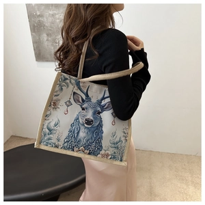 Detail of elegant canvas tote bag featuring a vintage deer print and woven handle straps