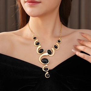 Close-up of vintage gold necklace with oval black gemstones on a model wearing V-neck