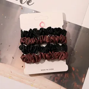 Detailed view of 4-piece satin scrunchies set in black and coffee brown on display card