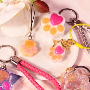 DIY cat paw resin molds with pink heart shakers and woven leather keychains on a white plate