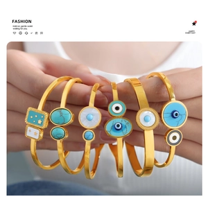 Detail view of a 6-piece golden Evil Eye bracelet set with blue and white enamel details