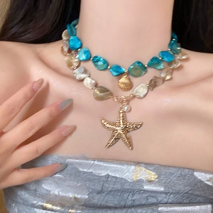 Double-layered starfish and shell pendant necklace with blue and beige beads on neck