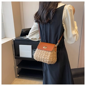 Close-up of handmade straw crossbody bag with brown leather flap and golden twist lock