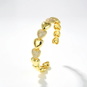 Dettaglio del bracciale a cuore dorato con pavé di zirconi e maglie geometriche cave