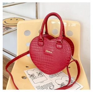 Vue détaillée du sac à main rouge en forme de cœur avec texture crocodile et bijoux dorés