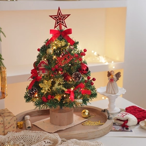 Mini tabletop Christmas tree with warm LED lights, red bows and ornaments on wooden base
