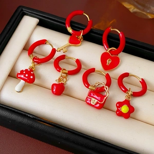 Detail of seven red enamel titanium earrings with heart, flower and key shapes in a jewelry box