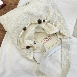 Détail du sac cabas en dentelle blanche avec poignées en perles colorées et crochets dorés