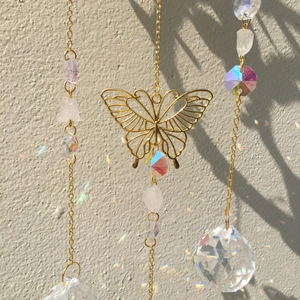 Golden butterfly crystal suncatcher reflecting rainbow light patterns on the wall