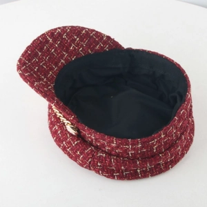 Detail of red tweed newsboy cap with gold chain accent and metallic threading texture
