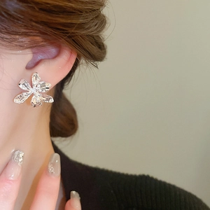 Close-up of a silver floral earring with liquid metal texture on a model's ear