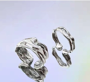 Macro shot of silver irregular ripple texture on an adjustable open ring with metallic finish
