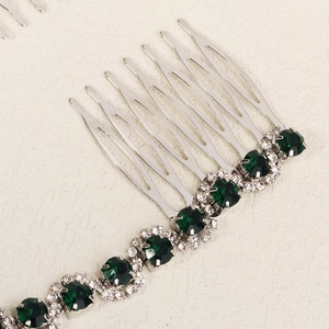 Detail view of silver bridal hair comb with emerald green gemstone and clear rhinestones