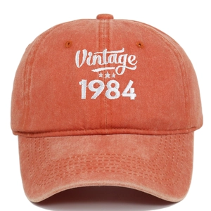 Detailed close-up of Vintage 1984 white embroidery on orange washed cotton baseball cap