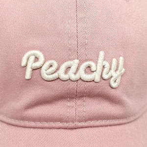 Close-up of pink cotton baseball cap with white 3D Peachy embroidery and twill texture