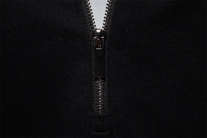 Macro shot of high-quality gunmetal zipper on black high-density cotton knit sweatshirt