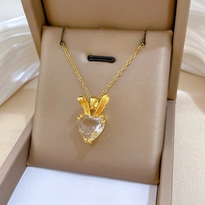 Close-up of gold heart zircon necklace with rabbit ear design in a velvet jewelry box