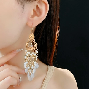 Detail shot of vintage bohemian gold tassel earrings with white beads on a model