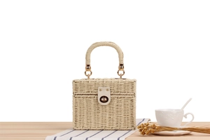 Close-up of woven beige box bag with leather patch and golden metallic twist lock