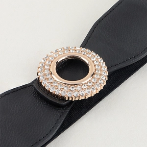 Detail of a black belt featuring a gold circular buckle encrusted with shiny rhinestones