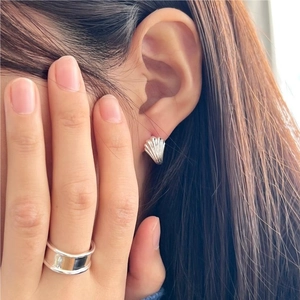 Macro view of silver shell stud earrings and wide minimalist ring on a female model