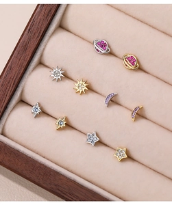 Macro detail of S925 silver celestial earrings set with sun, moon, and planet charms
