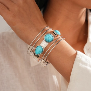 Detail of bohemian silver bangles with turquoise stones on female wrist close-up